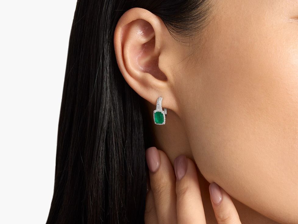 Close up of woman wearing emerald and diamond drop earrings